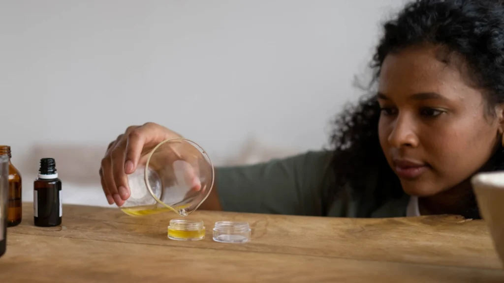 woman pouring cannabis muscle balm into jars